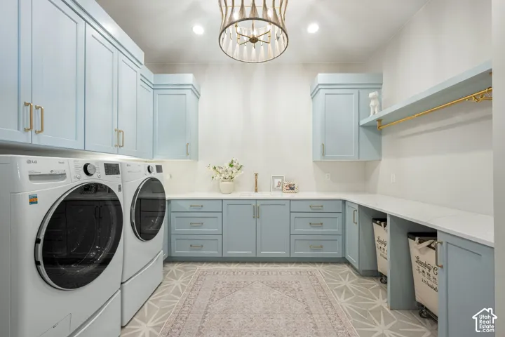 Laundry room featuring pale blue custom cabinetry, quartz countertops, a brass-finish hanging rod, geometric tile flooring, and a decorative pendant light fixture