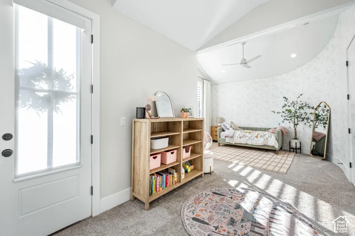 Vaulted ceiling featuring a central blade-style ceiling fan, curved accent wall, and glass-paneled exterior door