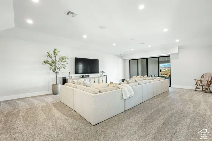 Spacious room featuring neutral carpeting, recessed ceiling lighting, and expansive glass sliding doors