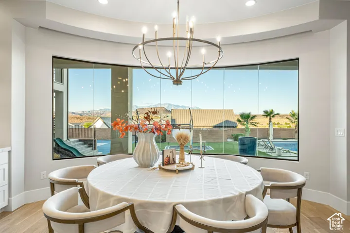 Curved wall of floor-to-ceiling windows, wood-finish flooring, recessed ceiling lighting, and custom chandelier