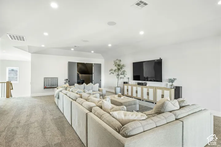 Recessed ceiling lighting, vaulted ceiling, neutral wall-to-wall carpeting, and double-door storage closet