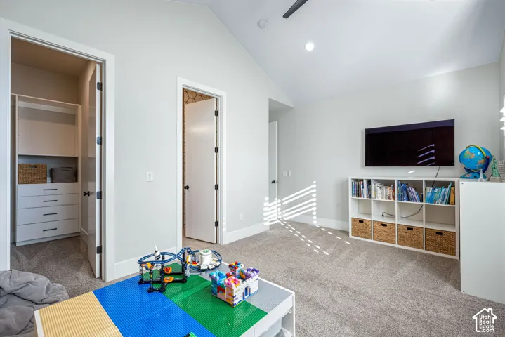 Vaulted ceilings, neutral wall color, wall-to-wall carpeting, and walk-in closet featuring built-in shelving