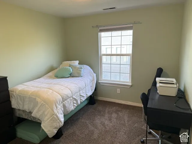 Neutral-toned interior space featuring wall-to-wall carpeting and a single-hung window with a grid pattern