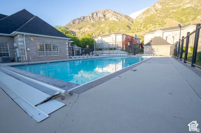 Outdoor swimming pool featuring concrete decking, a retractable pool cover, and prominent mountain backdrop