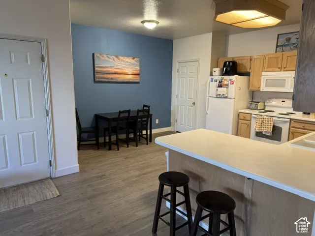 Kitchen featuring a peninsula with counter seating, wood-finish cabinetry, built-in microwave, and light-toned solid surface countertops