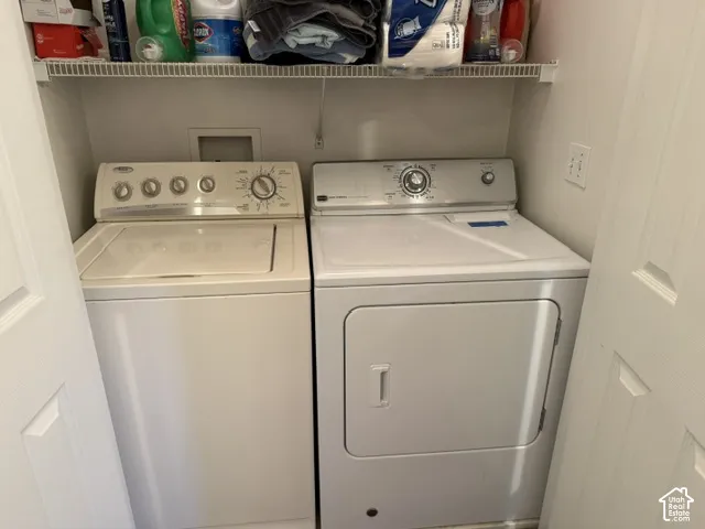 Laundry closet featuring wire shelving and a white top-loading washing machine and dryer set