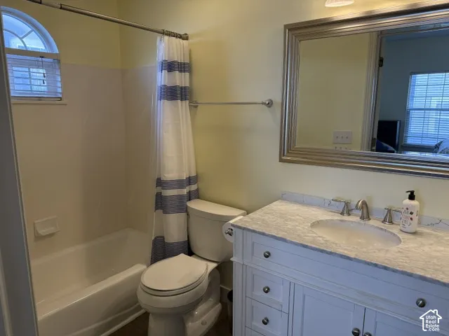 Bathroom featuring a white vanity with a stone-finish countertop, undermount sink, polished metal faucet, and an arched window