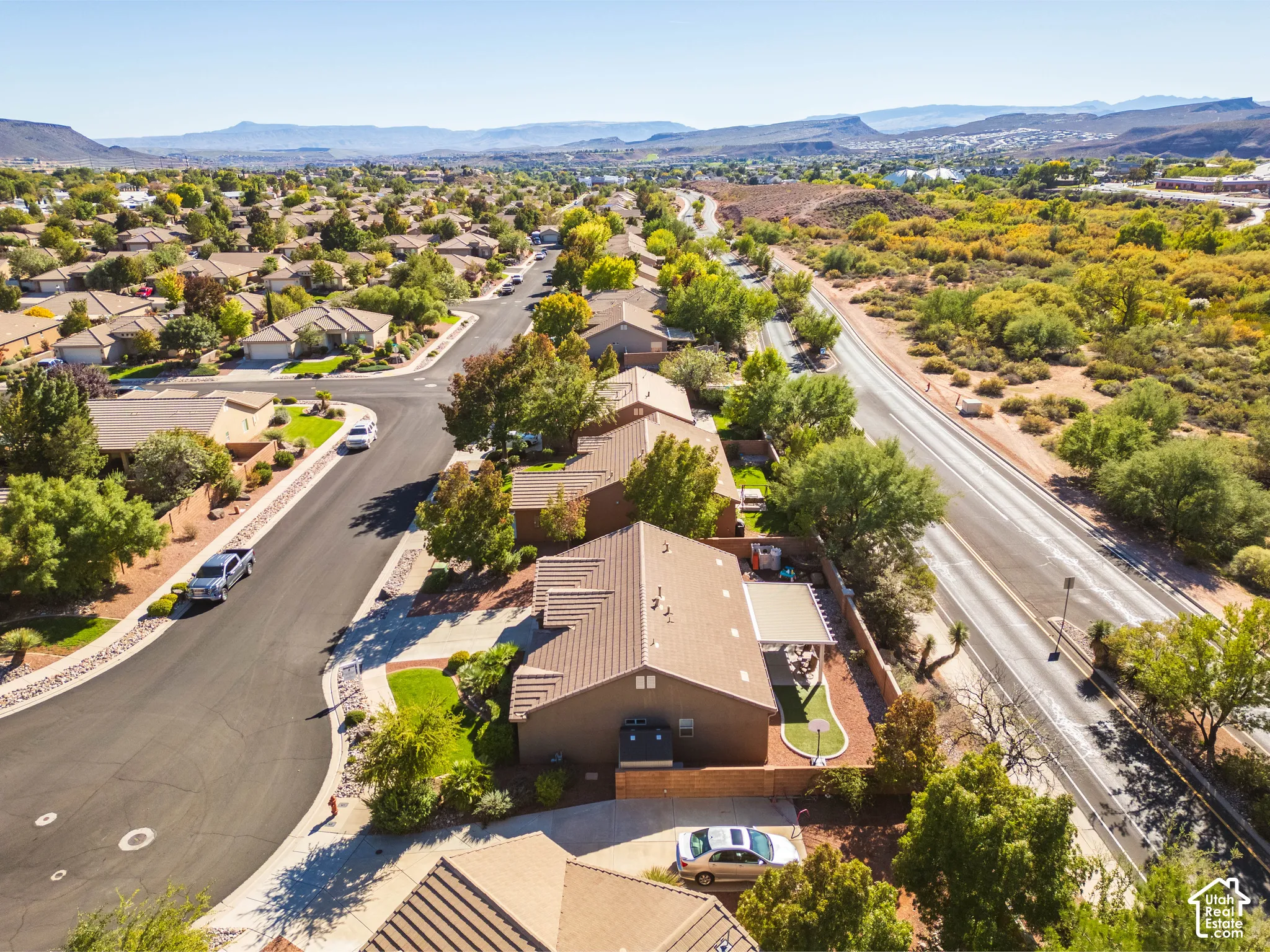 Aerial perspective featuring a tile-roofed residence, a rear covered patio, a masonry perimeter wall, and desert-inspired landscaping
