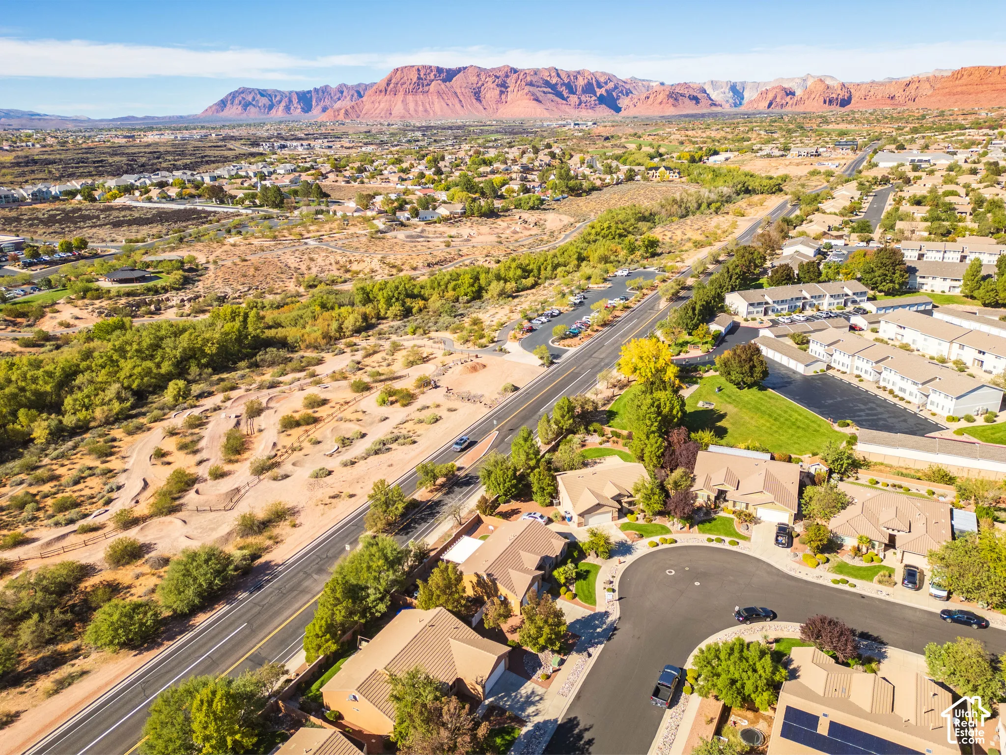 Aerial perspective featuring residential lots with pitched tile roofing, solar panel arrays, and mountain range scenery