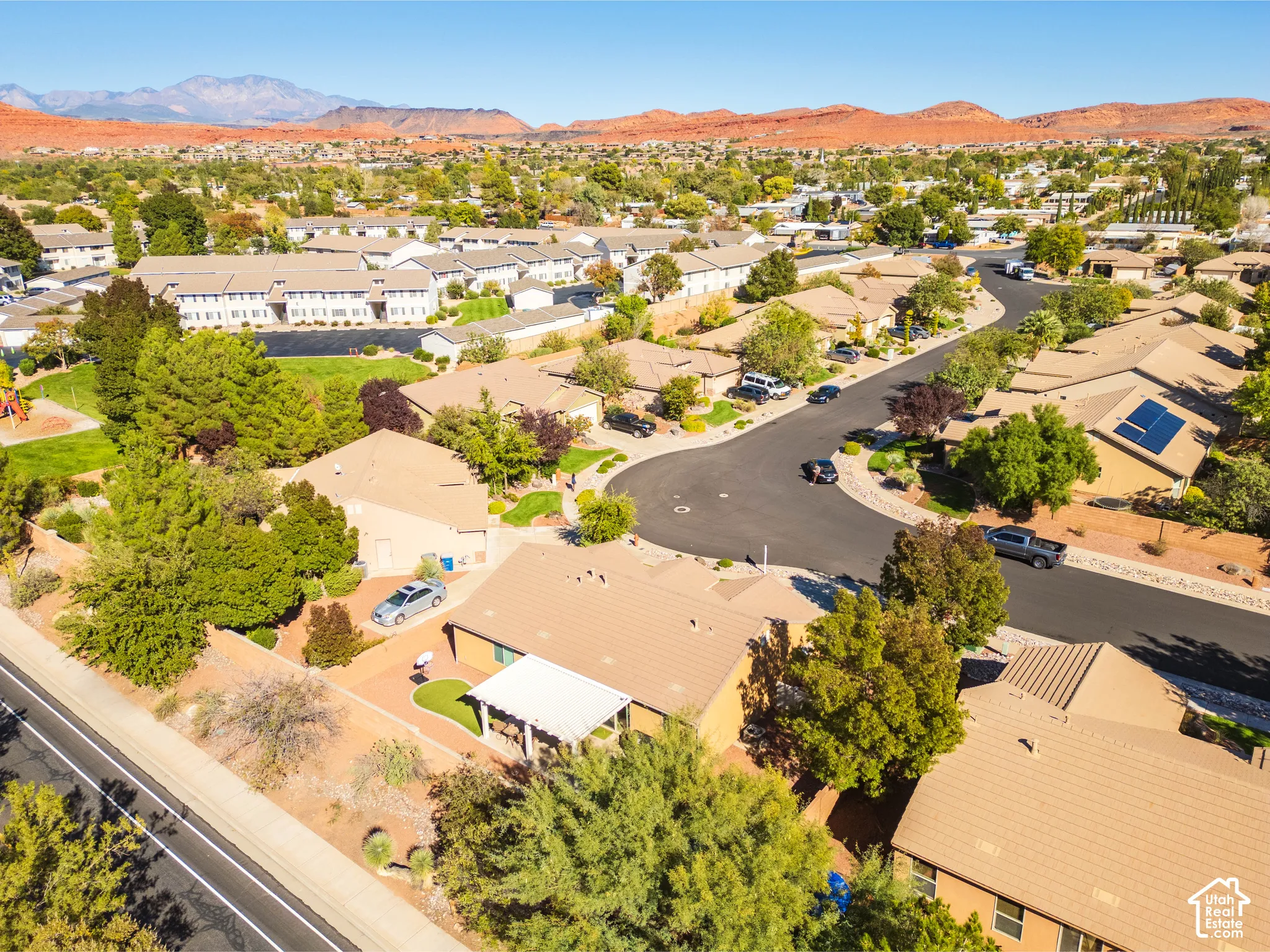 Aerial perspective of a residential property featuring a covered patio, native landscaping, and mountain backdrop