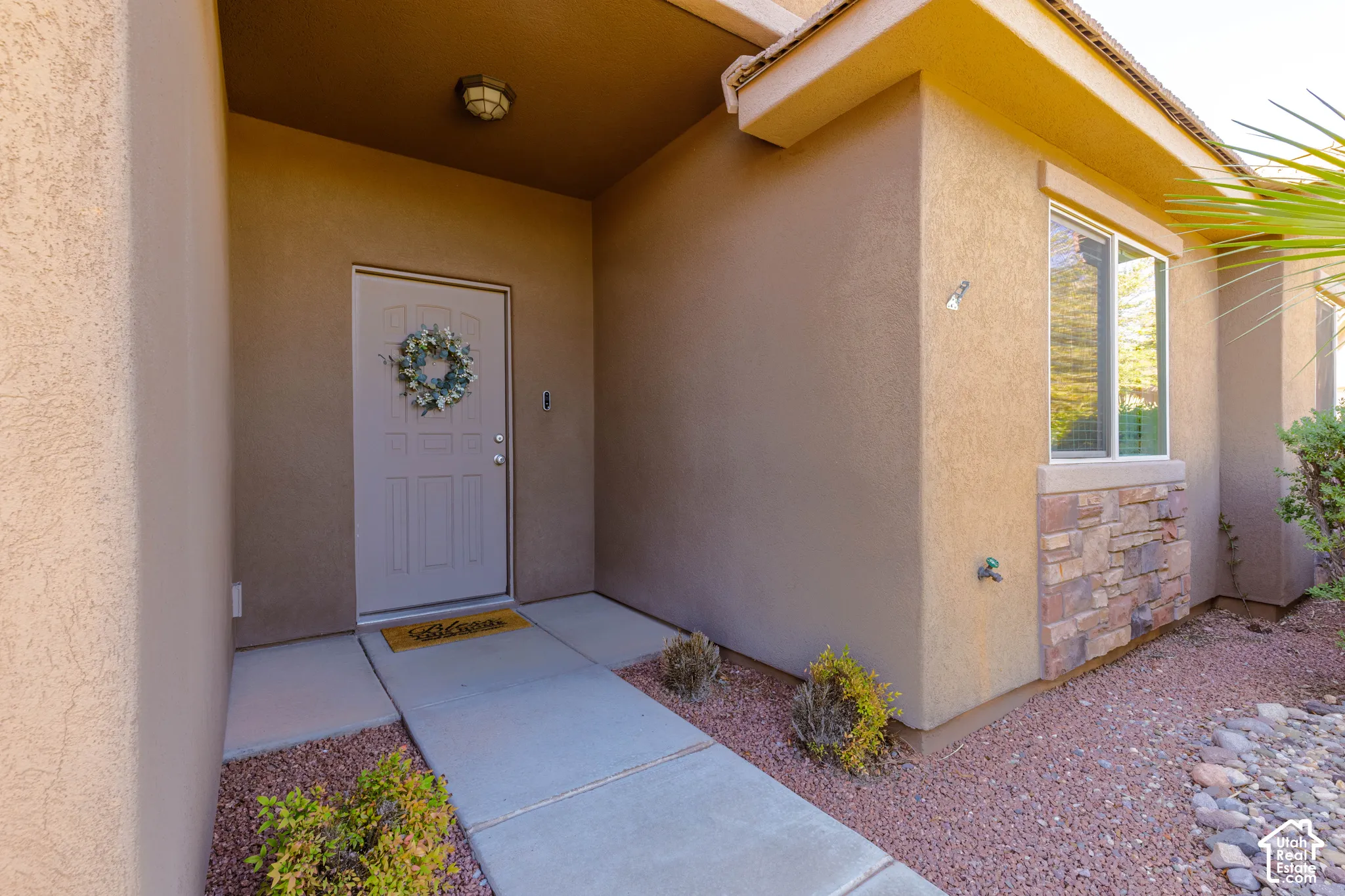 Covered entryway featuring a concrete walkway, exterior stucco siding, and stone veneer accents
