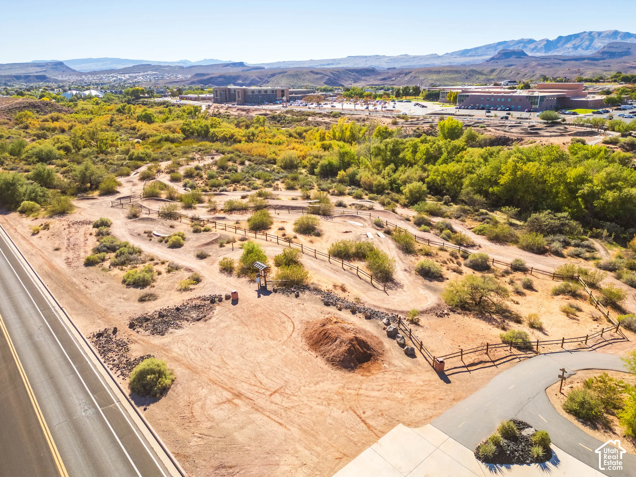 Expansive desert landscape featuring natural terrain, mature vegetation, rustic wood-rail fencing, and a mountainous backdrop