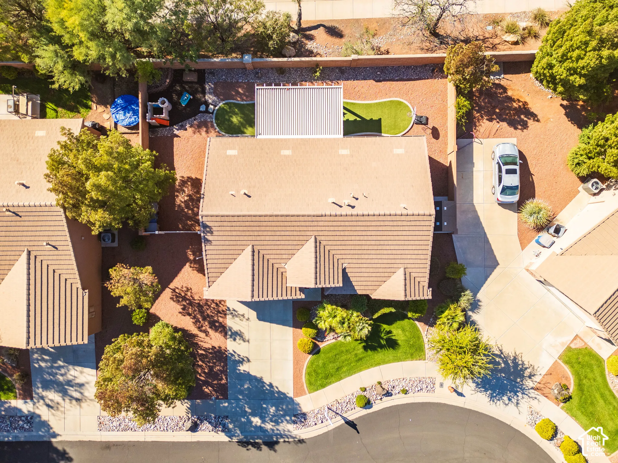 Aerial perspective of property featuring a tile roof, concrete driveway, covered rear patio, manicured front lawn, and perimeter masonry wall
