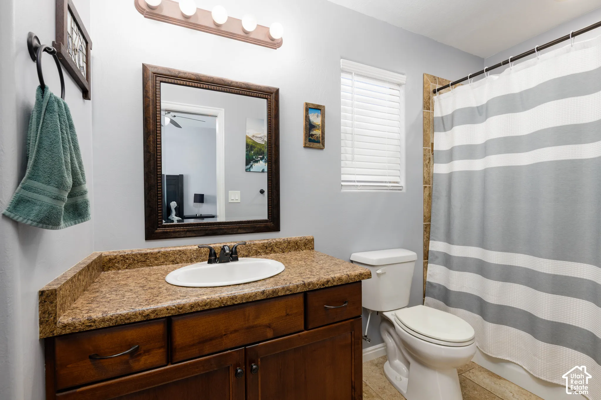 Bathroom featuring a dark wood vanity with stone-finish countertop, oval undermount sink, framed wall mirror, and tub-shower combination with tile surround