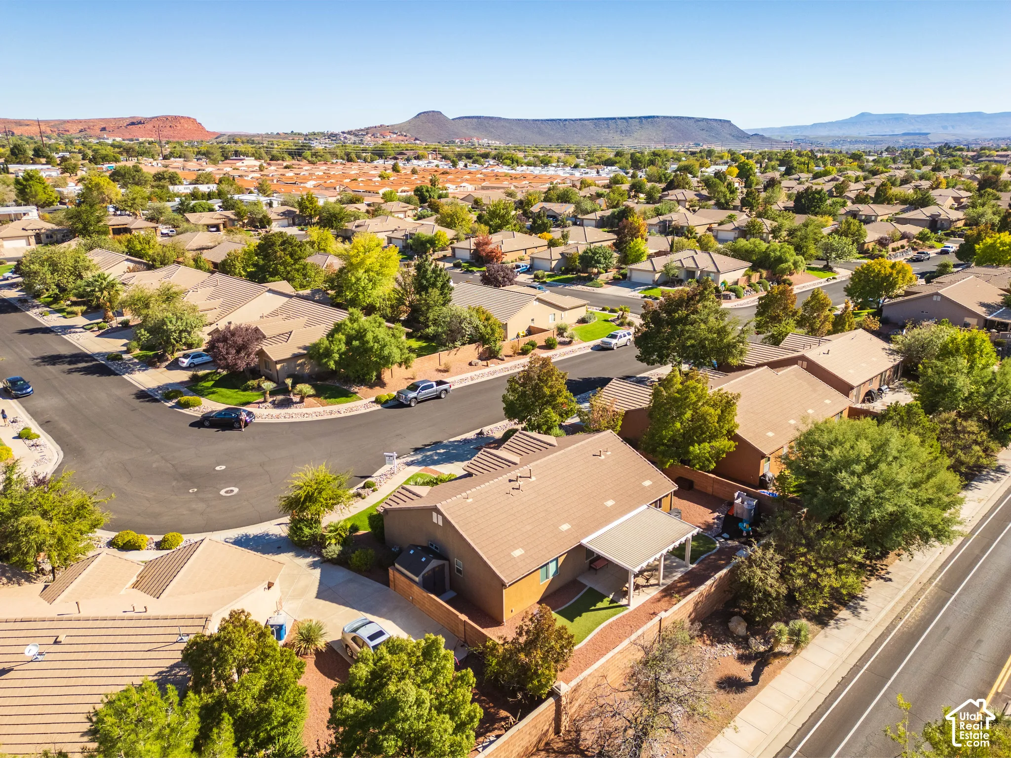 Corner-lot property featuring a tile roof, an attached patio cover, a fenced backyard, and a concrete driveway, set against a backdrop of desert mountains