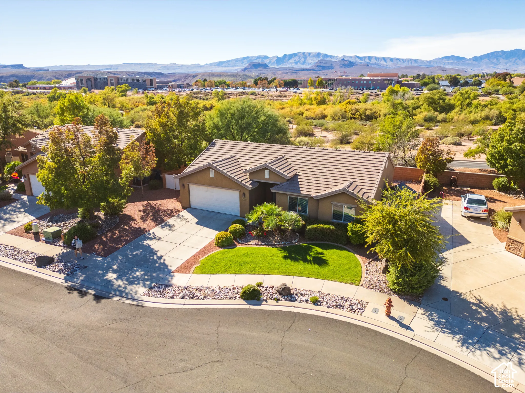 Single-story residence featuring a concrete tile roof, attached two-car garage, manicured front lawn, desert landscaping, and mountain backdrop