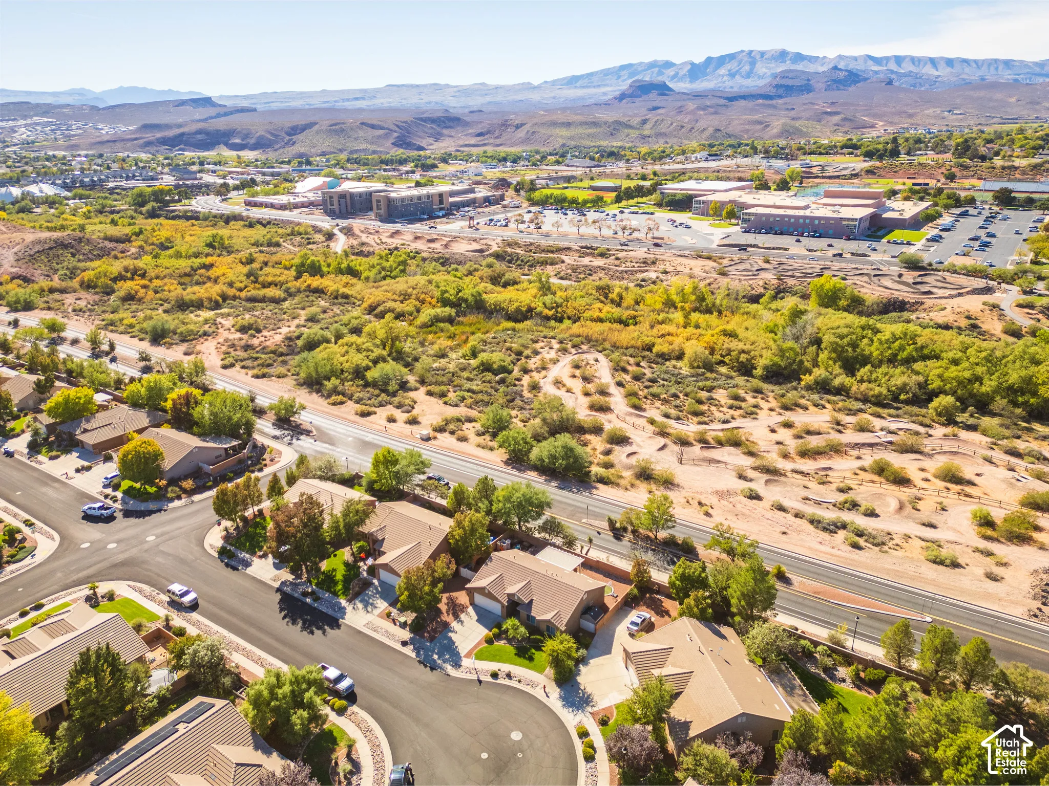 Aerial perspective featuring suburban residential streets, desert landscape, and prominent mountain range backdrop