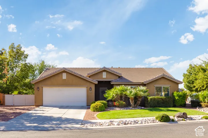 Single-story exterior featuring a stucco facade, tile roof, concrete driveway, and attached two-car garage