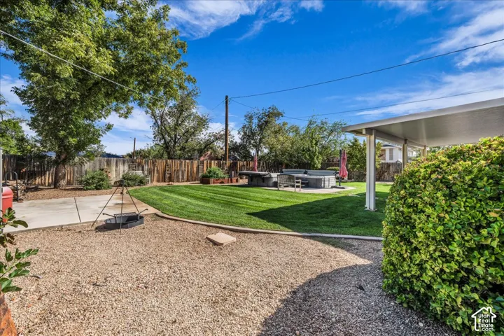 Backyard featuring a manicured lawn, gravel landscaping, a concrete patio, a covered patio area, and perimeter wood fencing