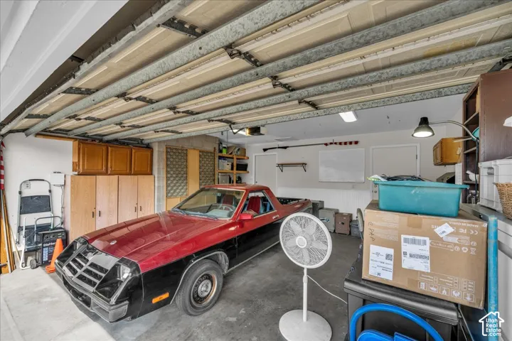 Multi-car garage featuring built-in wood cabinetry, overhead sectional door, and beadboard wall paneling