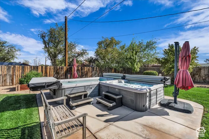 Backyard area featuring an L-shaped swim spa and integrated hot tub, concrete patio, and wood-slat perimeter fencing