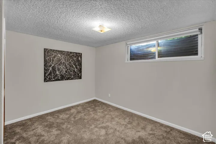 Interior room featuring neutral wall paint, wall-to-wall carpeting, a horizontal sliding window, and a square flush-mount ceiling light fixture