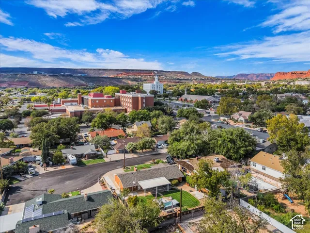 Aerial perspective showcasing residential neighborhood surroundings, mature trees, and prominent red rock mountain backdrop