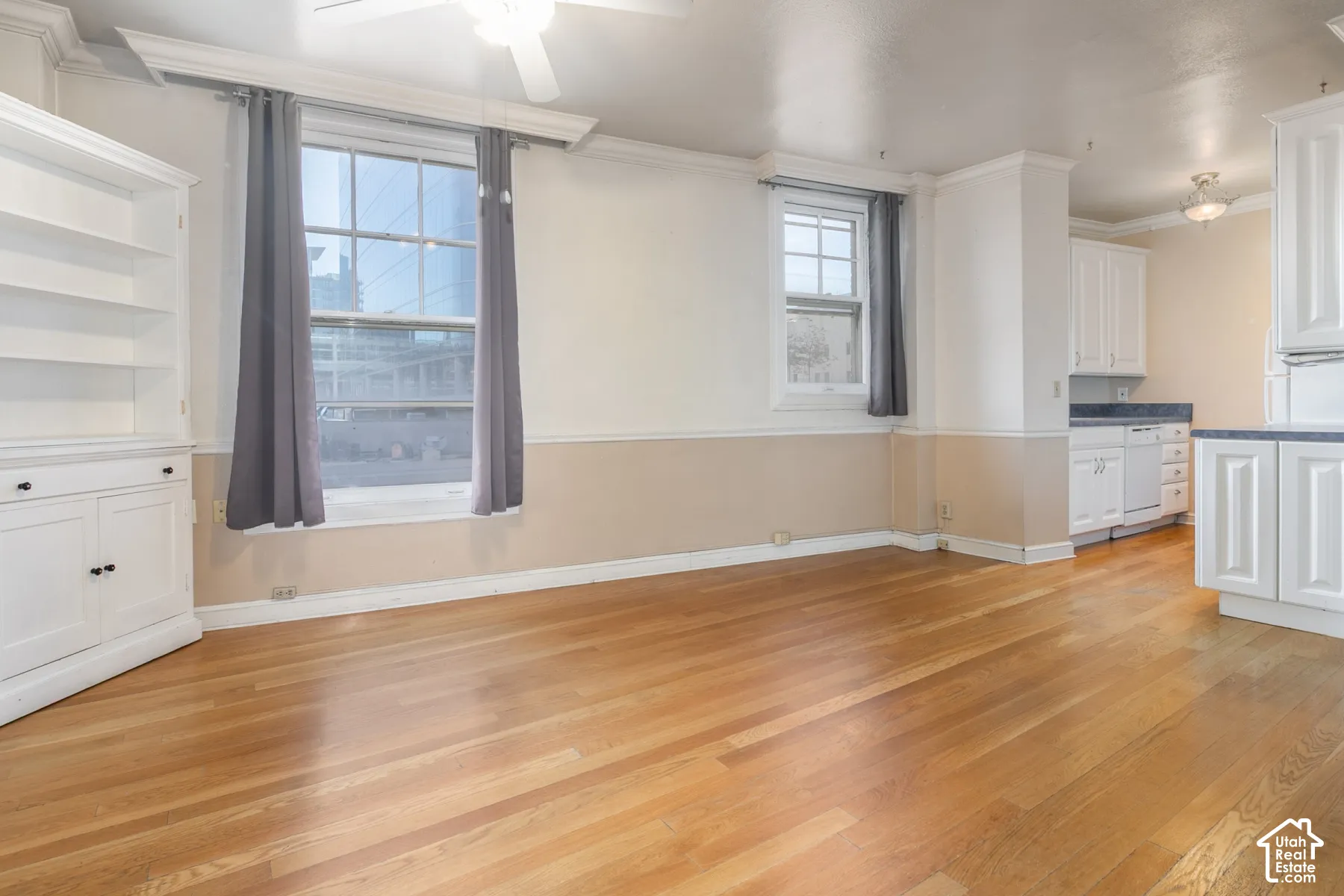 Interior space featuring wood-finish flooring, built-in white cabinetry, crown molding, and dual-tone wall trim
