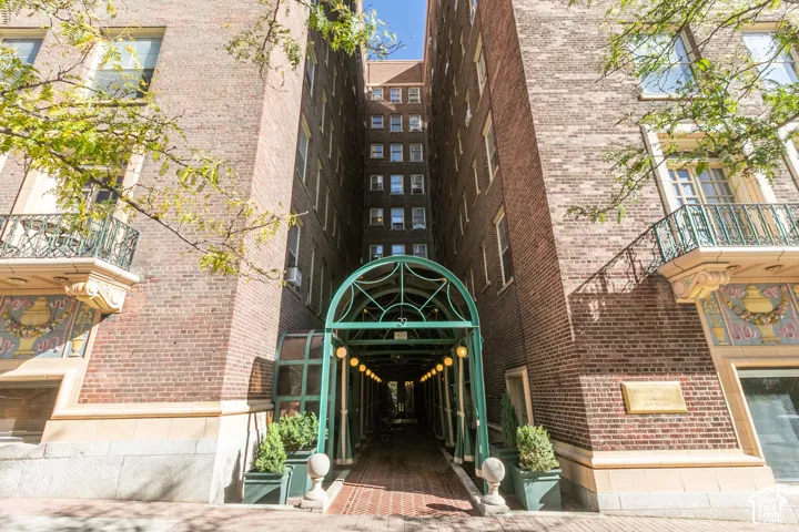 Multi-story brick exterior featuring a decorative arched metal entryway, symmetrical balcony detailing, and ornamental stone-finish accents