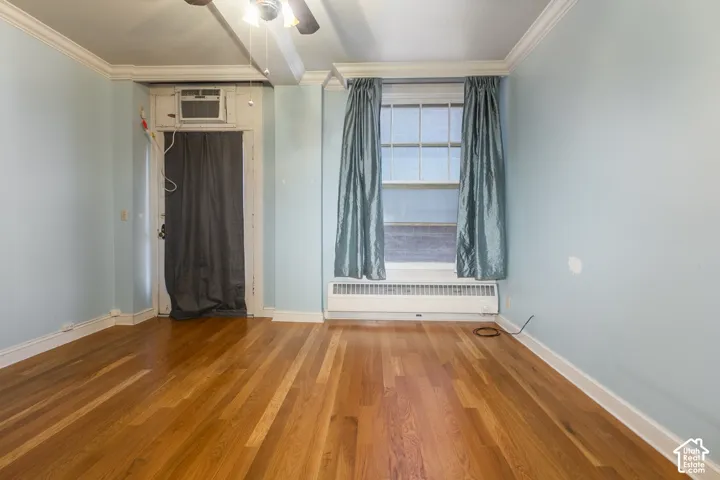 Interior space featuring wood-finish flooring, crown molding, and a multi-pane window
