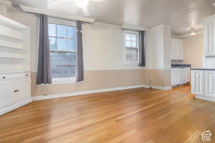 Interior space featuring wood-finish flooring, built-in white cabinetry, crown molding, and dual-tone wall trim