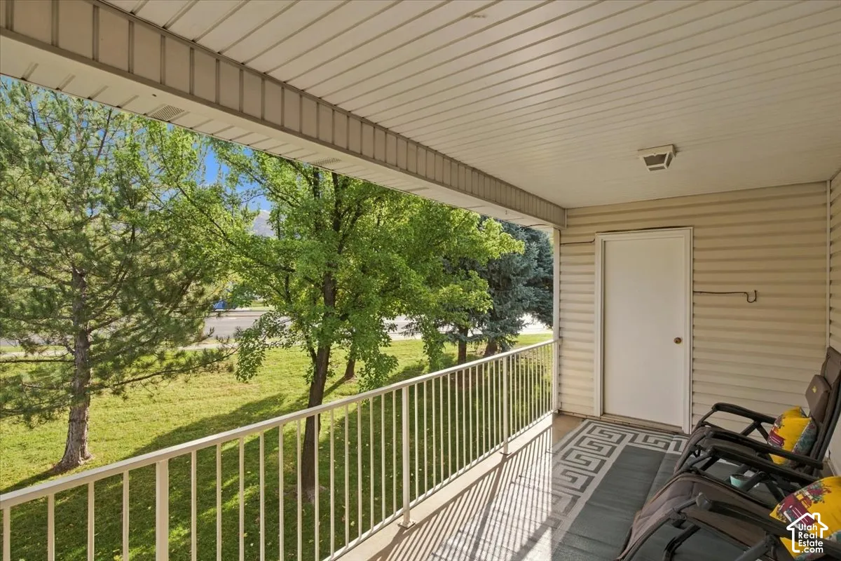 Covered balcony featuring vinyl siding, metal railings, and an exterior utility storage door