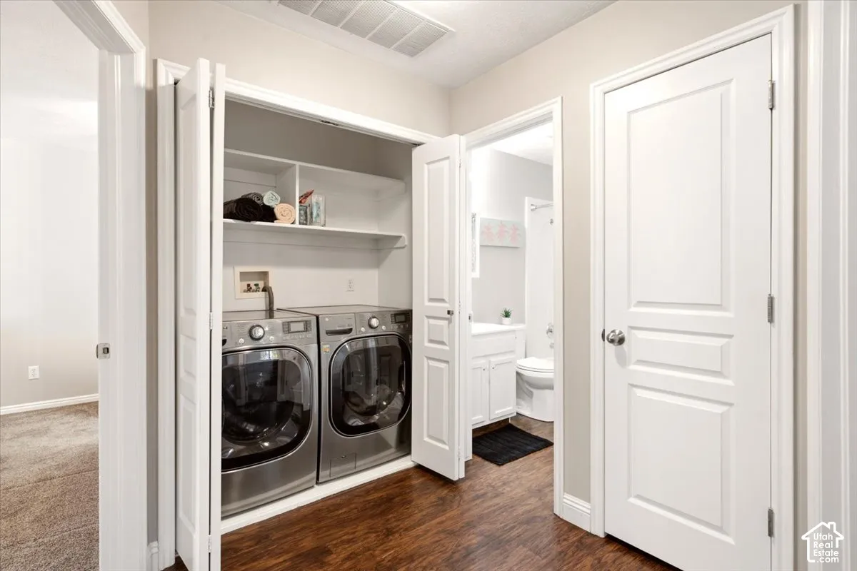 Laundry alcove with bifold doors, integrated overhead shelving, and wood-finish flooring