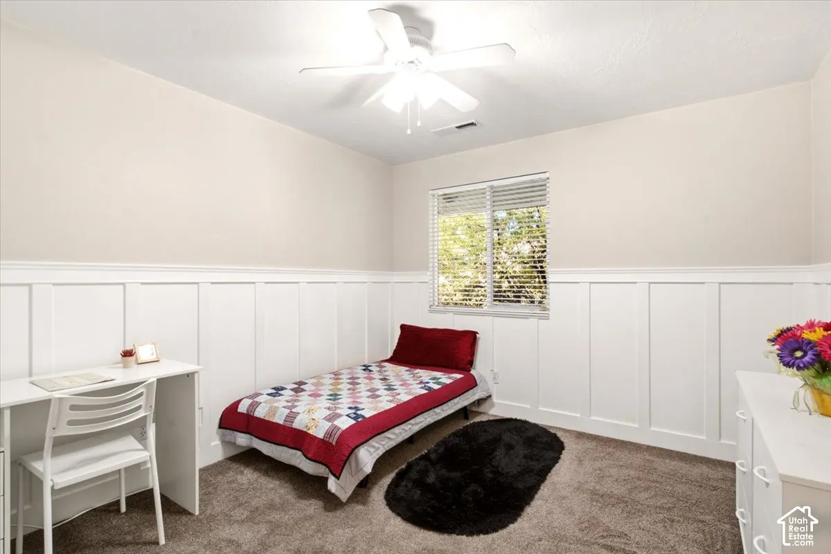Bedroom #2  featuring crisp white wainscoting, neutral wall tones, wall-to-wall carpeting, a ceiling fan, and blinds