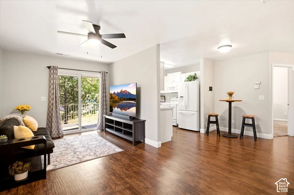 Open-concept interior featuring wood-finish flooring, a ceiling fan, sliding glass doors, and white cabinetry