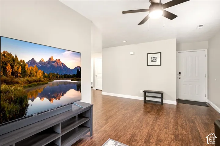 Open-concept living space featuring wood-finish flooring, neutral wall paint, and a ceiling-mounted light fixture with integrated fan