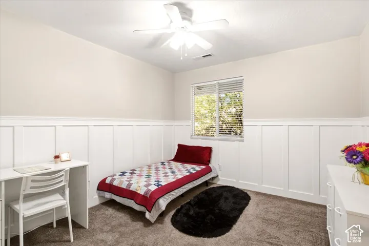 Bedroom #2  featuring crisp white wainscoting, neutral wall tones, wall-to-wall carpeting, a ceiling fan, and blinds