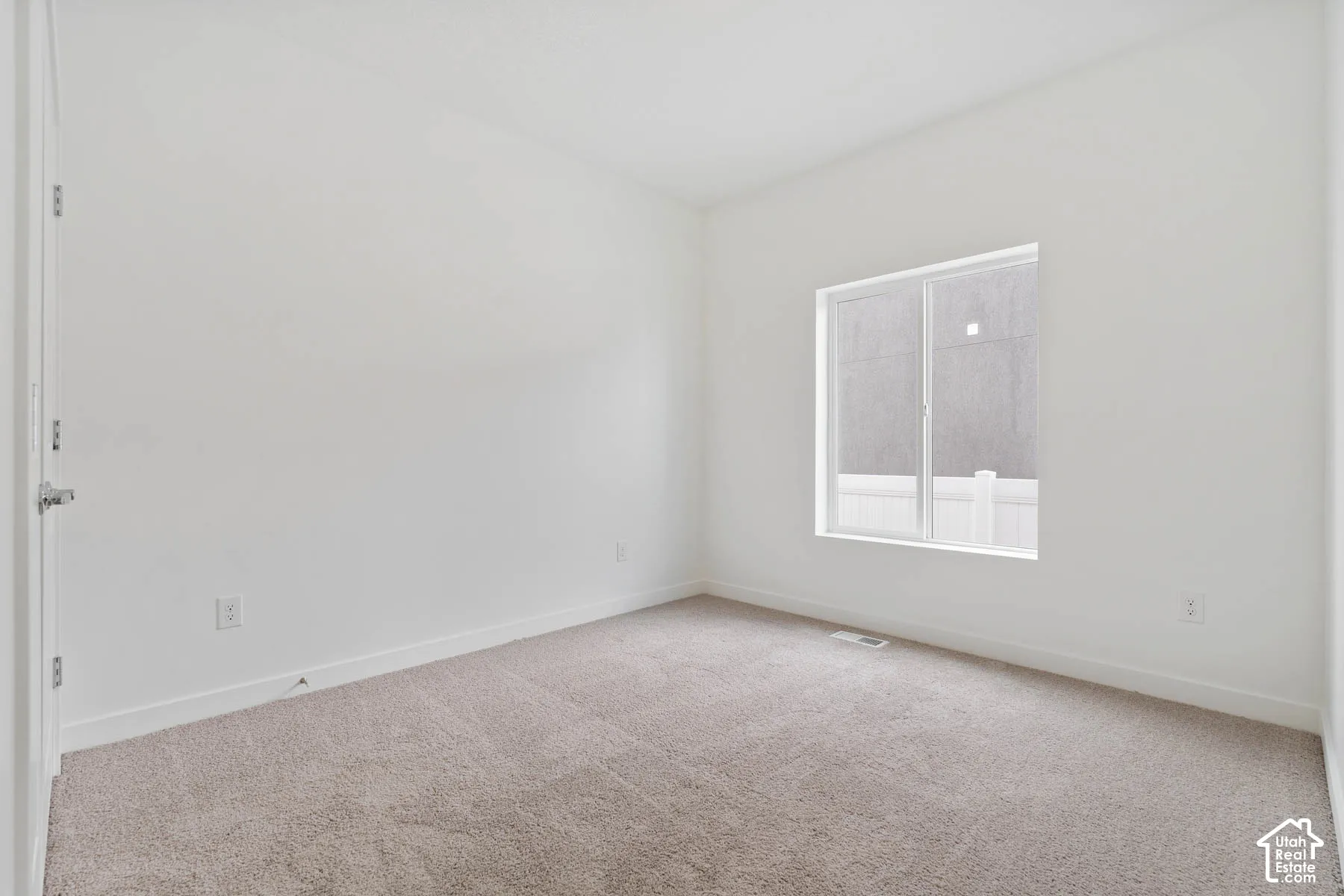 Neutral-toned carpet flooring, crisp white walls, and a single-pane sliding window