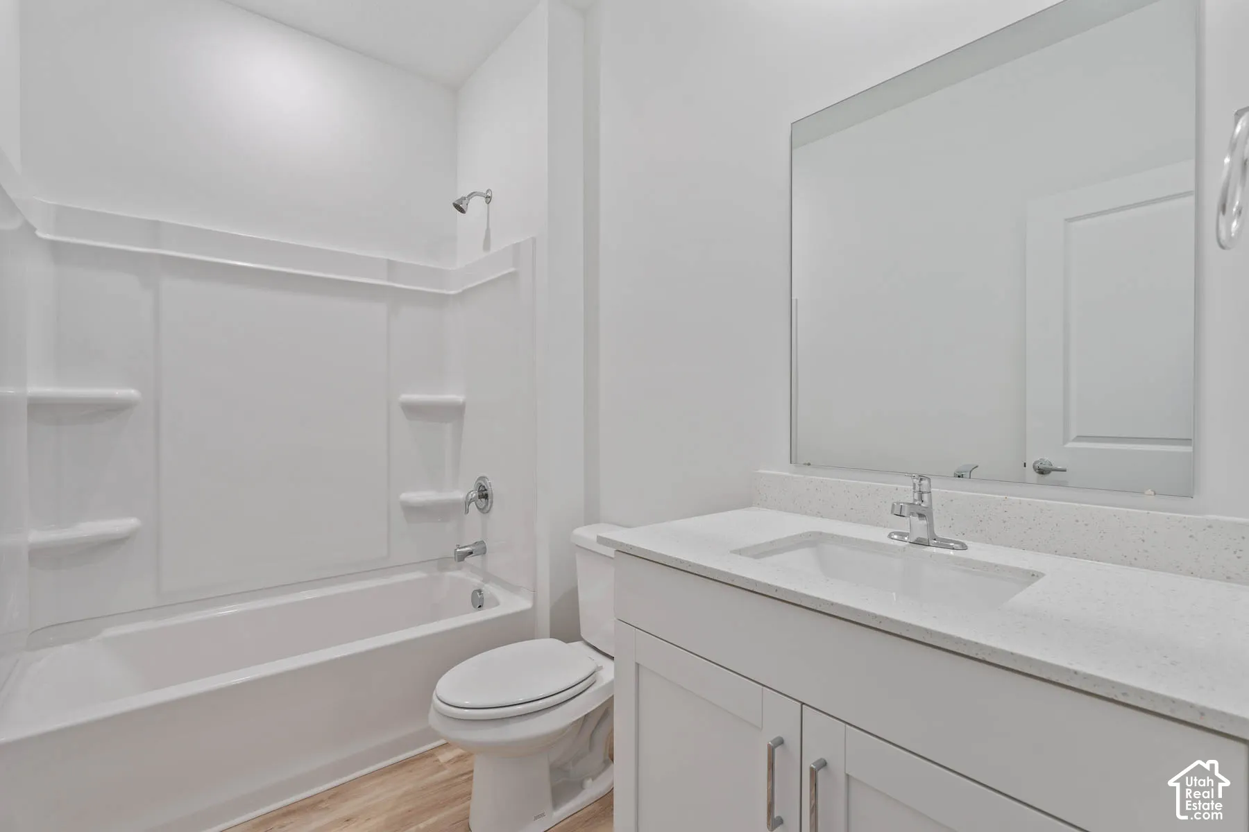 Bathroom featuring a white vanity with a composite countertop, an undermount sink, a full-width mirror, and a combined tub and shower surround