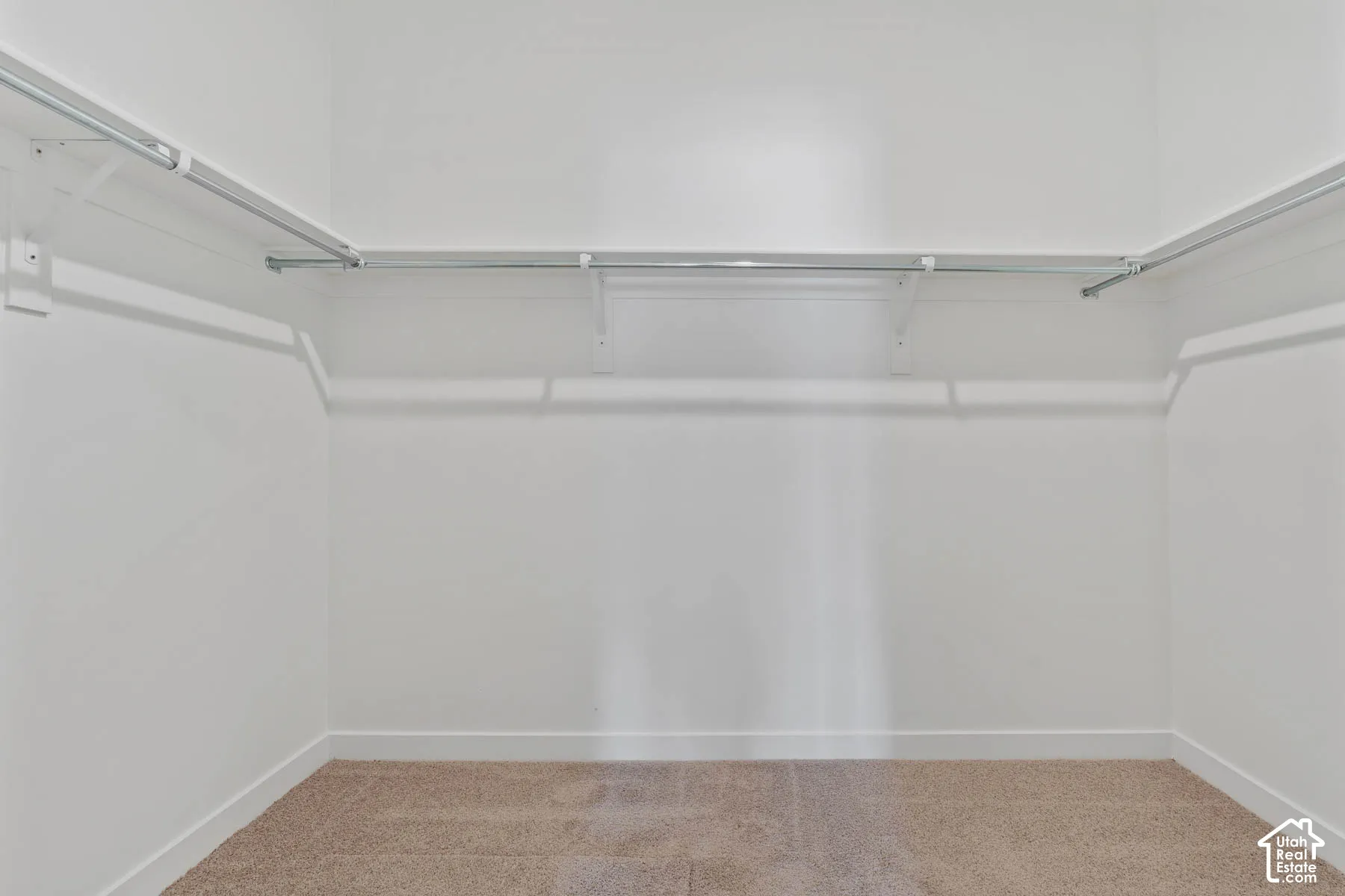 Walk-in closet featuring wall-to-wall carpeting and mounted metal garment rods