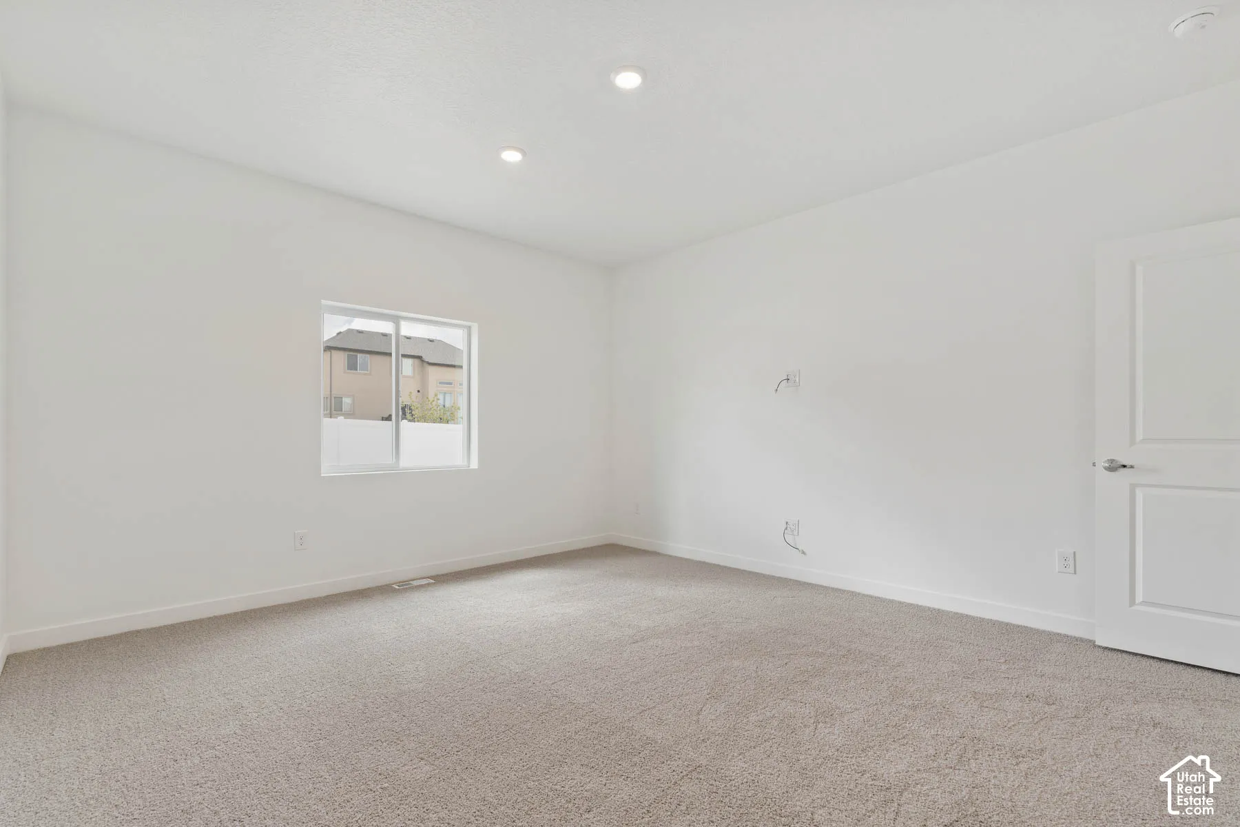Neutral-toned carpeting, recessed ceiling lighting, and a white two-panel interior door