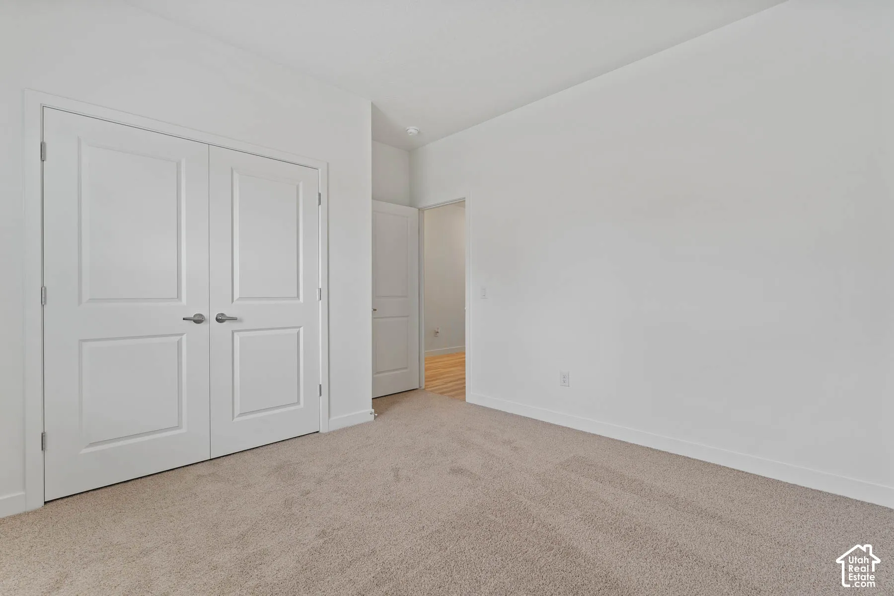 Neutral-toned wall-to-wall carpeting, double-panel closet doors with brushed nickel hardware, and clean white interior wall finish