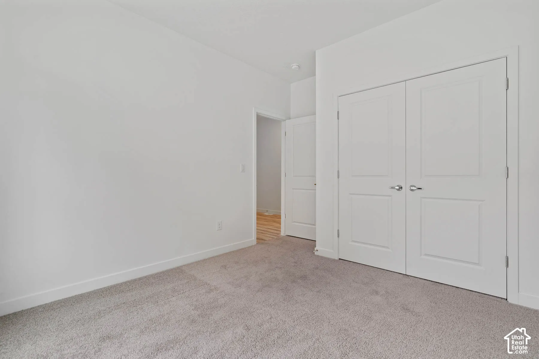 Neutral-toned wall-to-wall carpeting, double-panel closet doors, and multi-panel interior doors with metallic hardware