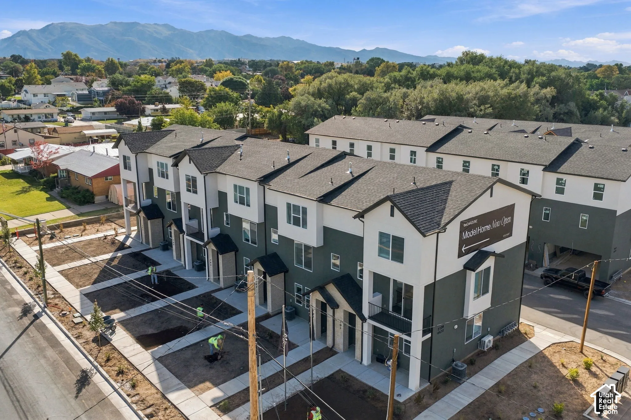 Multi-level townhome exterior featuring dual-tone siding, asphalt shingle roofing, private balconies, and mountain backdrop