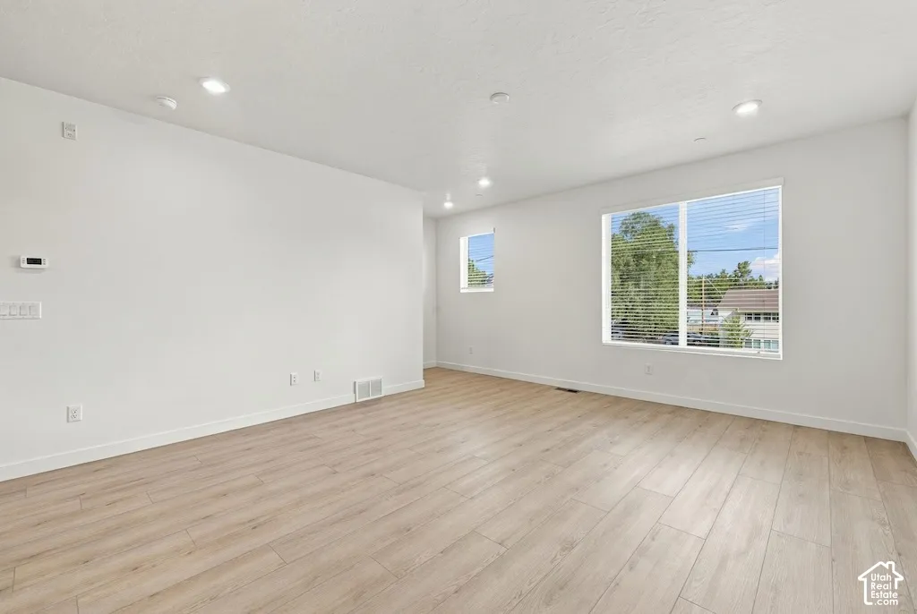 Neutral interior featuring wood-finish flooring, recessed lighting, and large windows with horizontal blinds