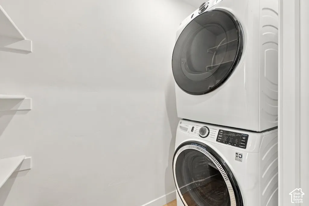 Laundry area featuring a stackable washer and dryer unit and built-in white shelving