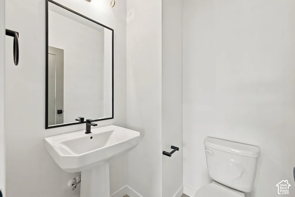 Pedestal sink with a single-handle matte black faucet, rectangular mirror with a matte black frame, and matching matte black hardware