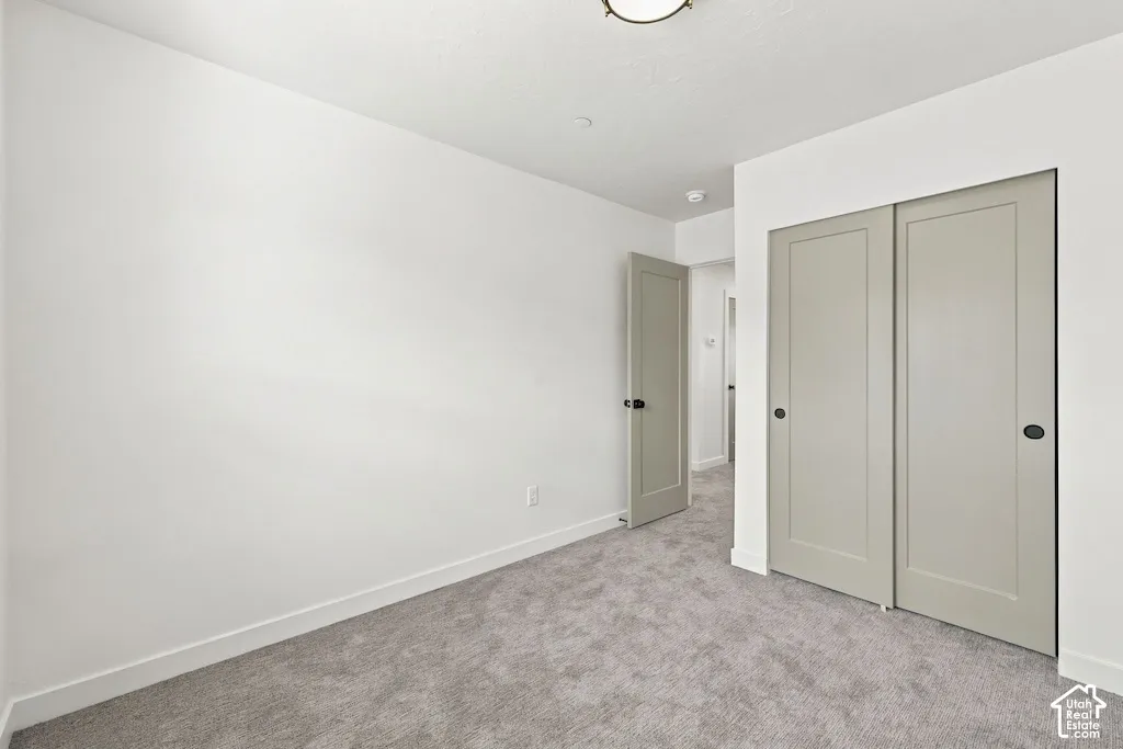 Neutral-toned interior space featuring wall-to-wall carpeting, shaker-style closet doors with recessed panels, and matte black hardware