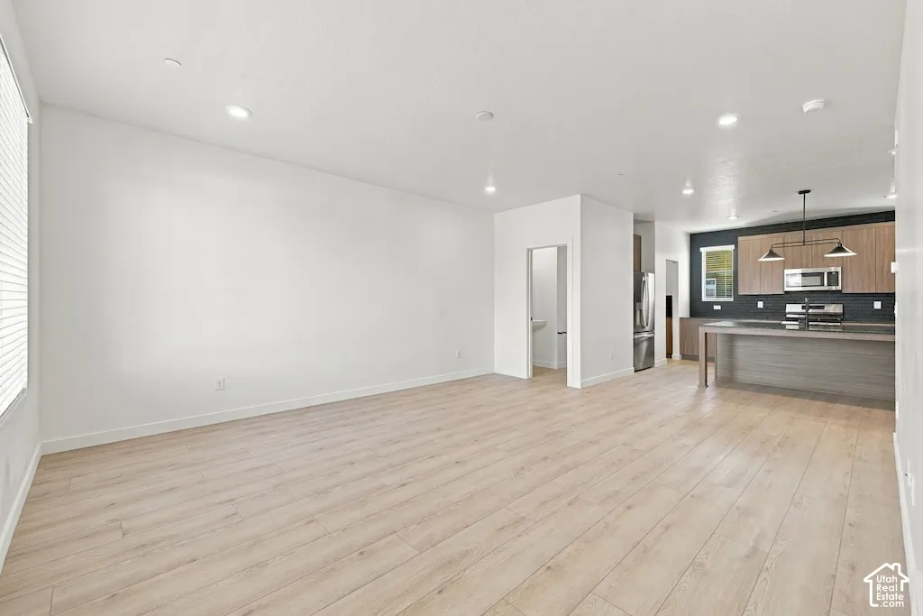 Open-concept floor plan featuring wood-finish flooring, recessed lighting, a kitchen island with stone countertop, and two-tone cabinetry