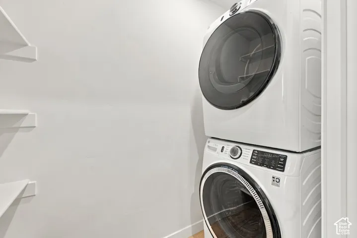 Laundry area featuring a stackable washer and dryer unit and built-in white shelving